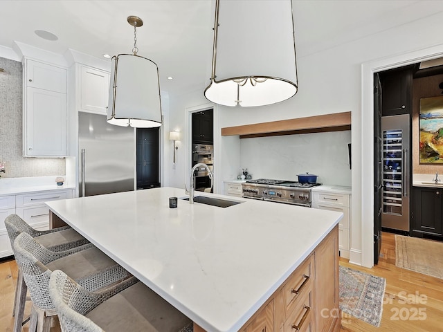 kitchen with a kitchen island with sink, light countertops, high quality appliances, and white cabinetry