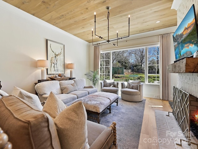 living area with wood ceiling, wood finished floors, a brick fireplace, a chandelier, and recessed lighting