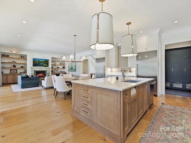 kitchen with an island with sink, pendant lighting, light countertops, and open floor plan