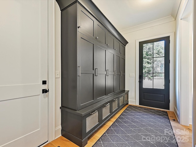 mudroom with crown molding, baseboards, and wood finished floors