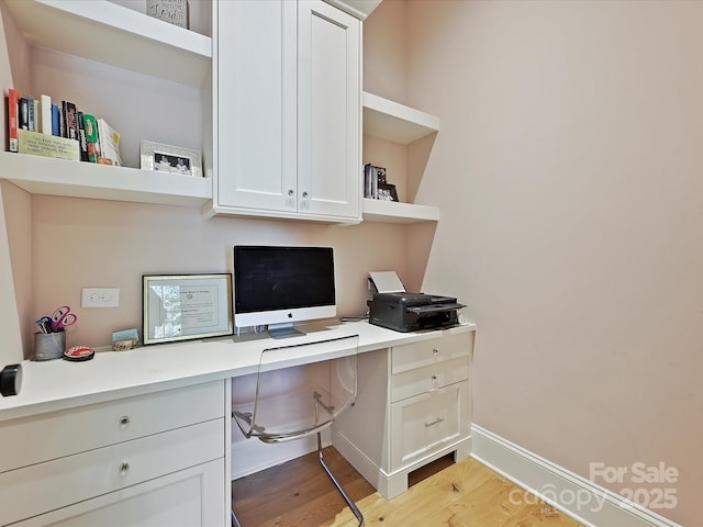 office area with built in study area, light wood-style flooring, and baseboards