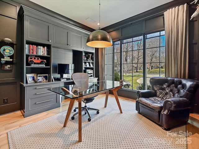 home office with built in features, visible vents, plenty of natural light, and light wood-style flooring