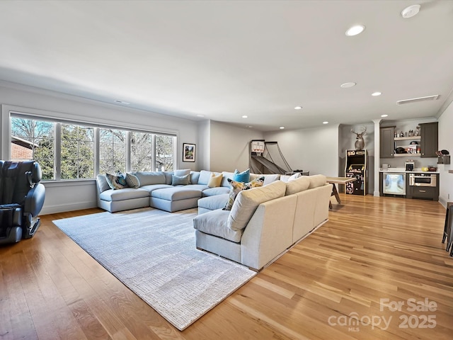 living room with recessed lighting, baseboards, light wood-style flooring, and a dry bar