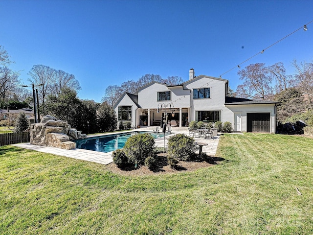 back of house with fence, a yard, a fenced in pool, a chimney, and a patio area