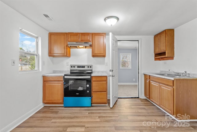 kitchen featuring stainless steel electric range oven, light wood-style flooring, light countertops, under cabinet range hood, and a sink