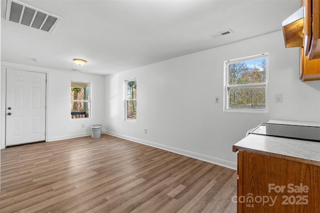 interior space with a healthy amount of sunlight, light wood finished floors, baseboards, and visible vents