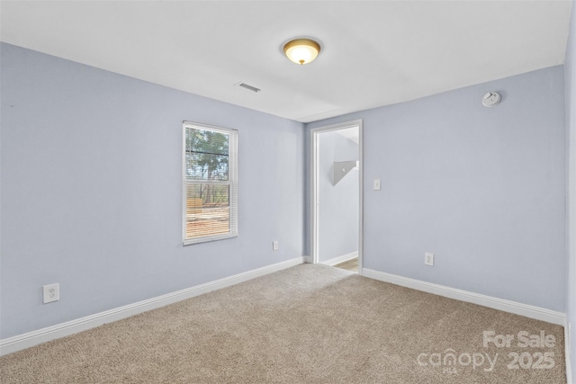 carpeted spare room featuring visible vents and baseboards