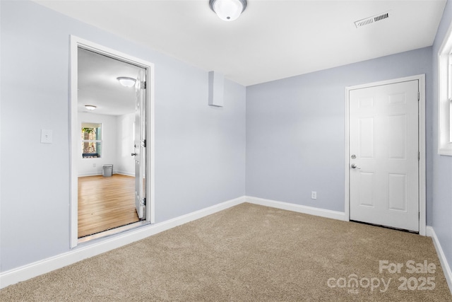 empty room with carpet flooring, visible vents, and baseboards