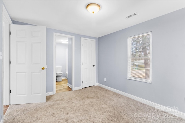 unfurnished bedroom with light colored carpet, ensuite bath, visible vents, and baseboards