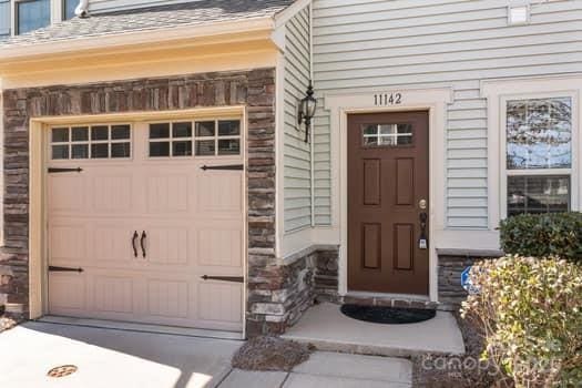 property entrance with a garage, concrete driveway, and stone siding