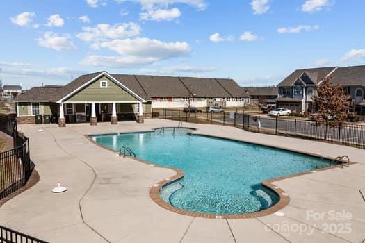 community pool featuring a patio area, a residential view, and fence