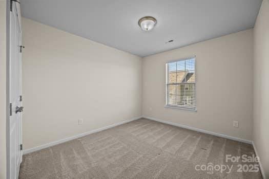 carpeted spare room featuring baseboards