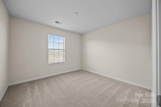 carpeted empty room featuring baseboards