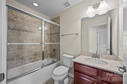 full bathroom featuring visible vents, vanity, toilet, and bath / shower combo with glass door