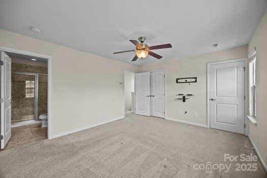 unfurnished bedroom featuring baseboards, a ceiling fan, ensuite bathroom, carpet floors, and a closet