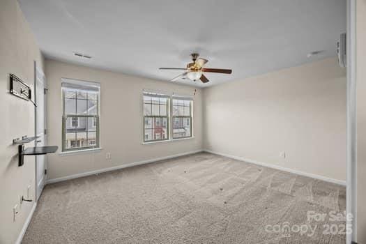 spare room with carpet floors, ceiling fan, and baseboards