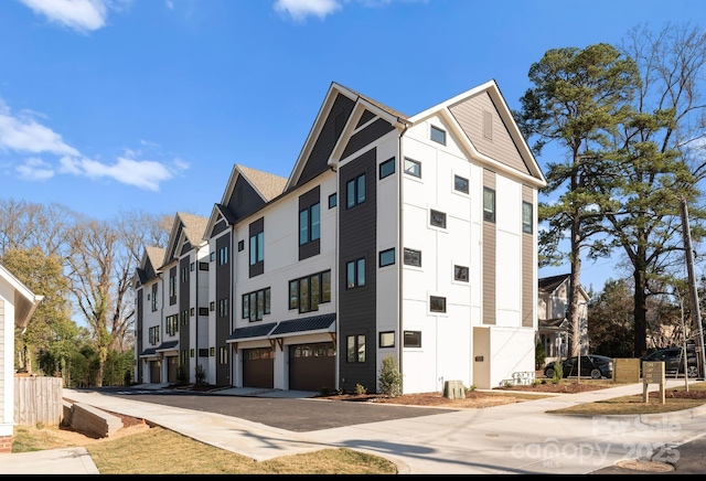 view of building exterior featuring driveway, an attached garage, and a residential view