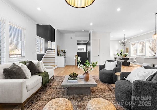 living area with stairs, crown molding, an inviting chandelier, and wood finished floors