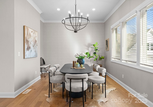 dining area featuring light wood finished floors, baseboards, visible vents, and ornamental molding