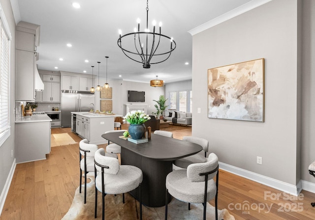 dining area featuring a chandelier, recessed lighting, baseboards, ornamental molding, and light wood-type flooring