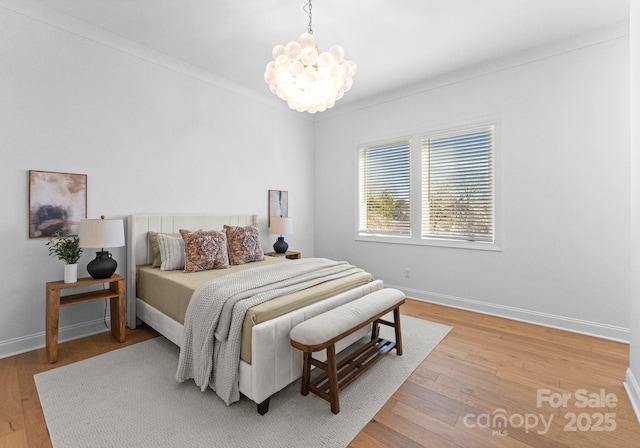 bedroom with crown molding, baseboards, a notable chandelier, and hardwood / wood-style floors