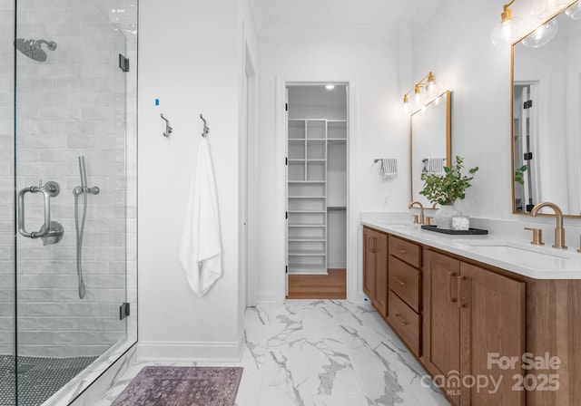 bathroom with marble finish floor, a spacious closet, a stall shower, and a sink