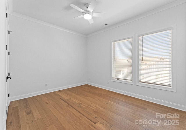 empty room featuring baseboards, a ceiling fan, light wood-style flooring, and crown molding