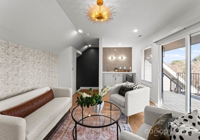 living area featuring beverage cooler, vaulted ceiling, a bar, and wood finished floors