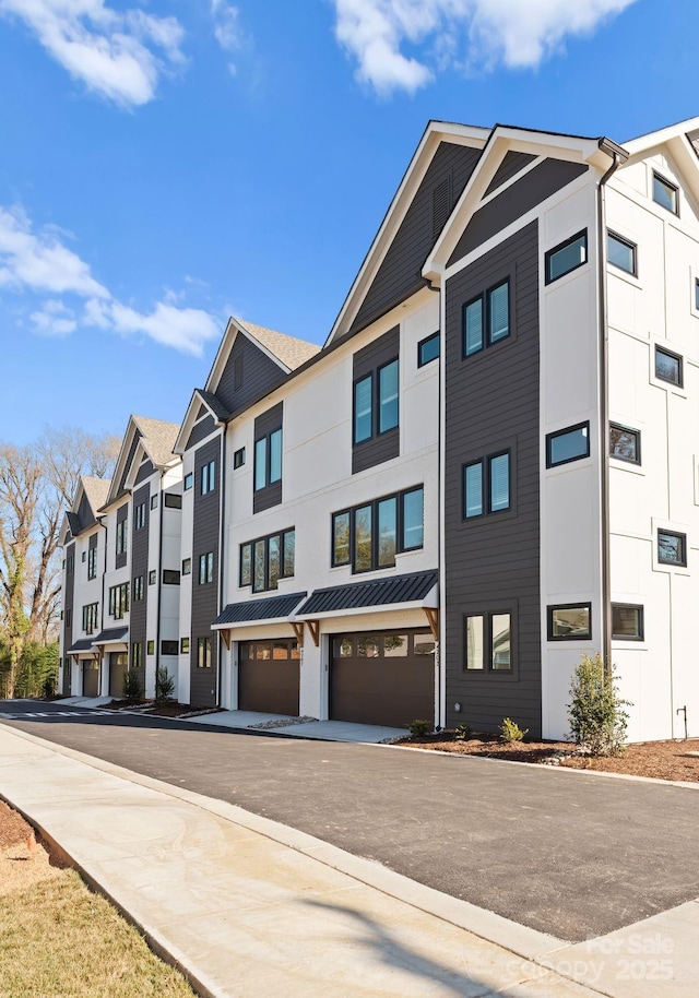 townhome / multi-family property featuring a standing seam roof, metal roof, and an attached garage