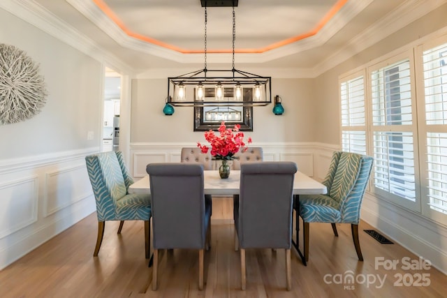 dining space with wood finished floors, a raised ceiling, and visible vents