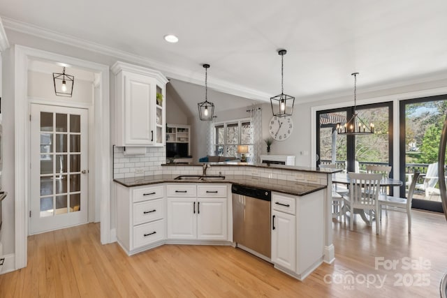 kitchen with tasteful backsplash, white cabinets, a peninsula, stainless steel dishwasher, and a sink