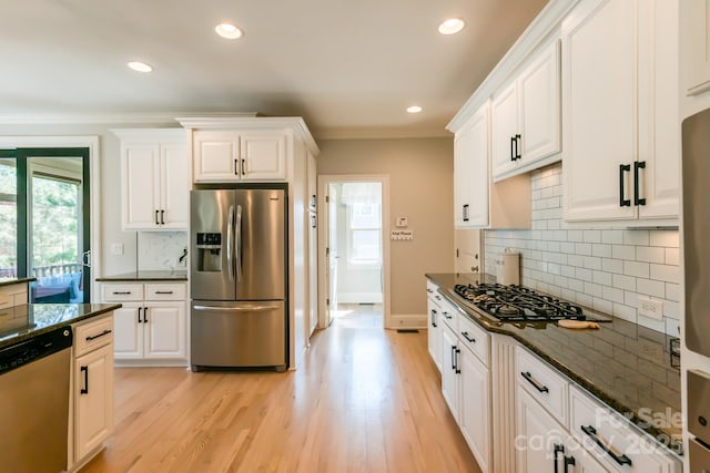 kitchen featuring stainless steel appliances, ornamental molding, light wood-type flooring, and white cabinets