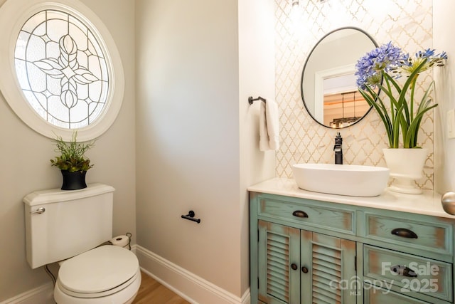 half bathroom with toilet, vanity, and baseboards