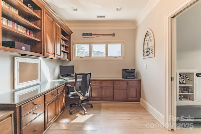 office with baseboards, visible vents, built in study area, crown molding, and light wood-type flooring