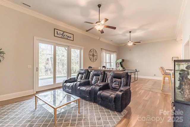 living room featuring baseboards, light wood-style flooring, visible vents, and crown molding