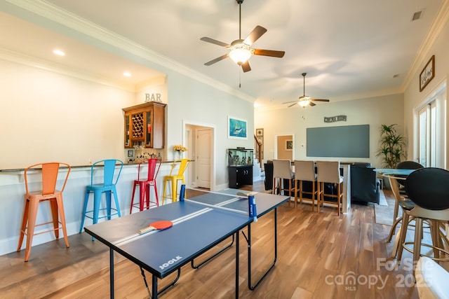 playroom featuring visible vents, ornamental molding, wood finished floors, wet bar, and baseboards