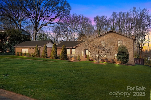 view of front of house with brick siding and a yard