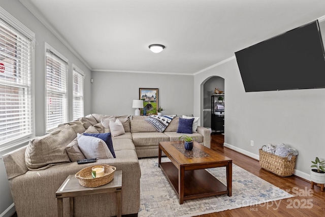 living area with arched walkways, ornamental molding, baseboards, and wood finished floors