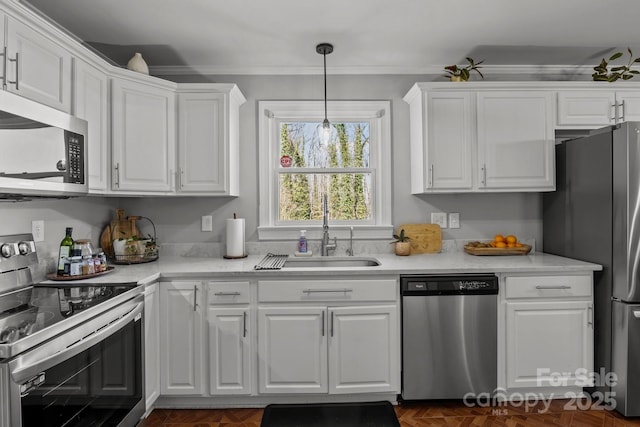 kitchen featuring light countertops, ornamental molding, appliances with stainless steel finishes, white cabinets, and a sink