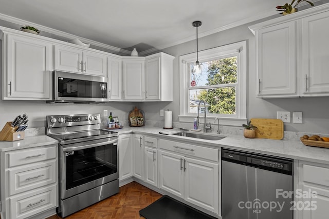 kitchen with crown molding, appliances with stainless steel finishes, hanging light fixtures, white cabinets, and a sink