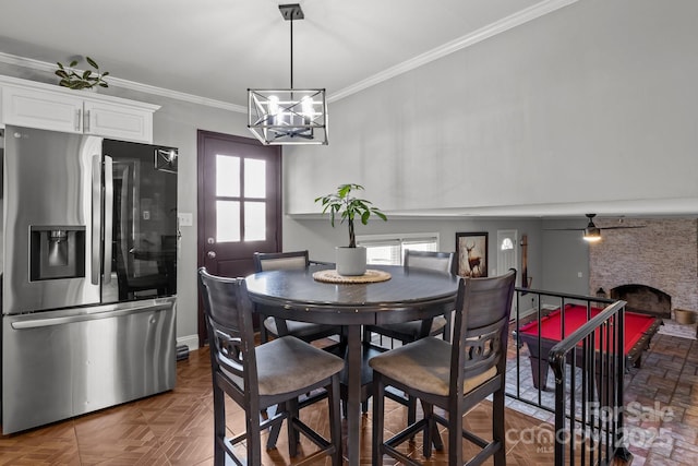 dining area with crown molding, a notable chandelier, and a fireplace