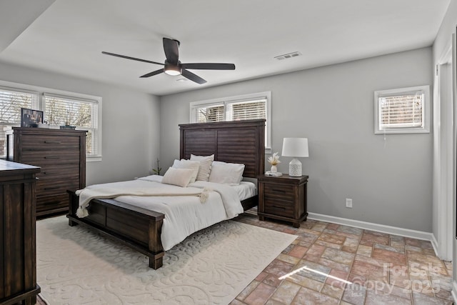 bedroom featuring multiple windows, visible vents, baseboards, and ceiling fan