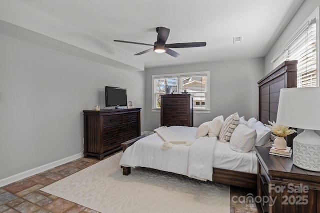 bedroom featuring visible vents, stone finish floor, a ceiling fan, and baseboards