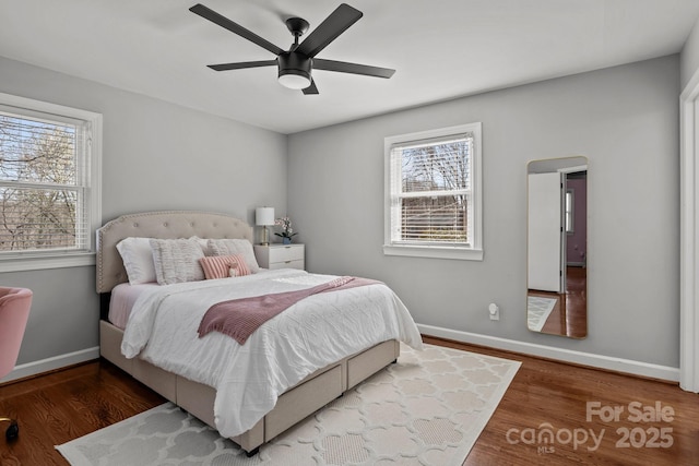 bedroom with multiple windows, wood finished floors, and baseboards