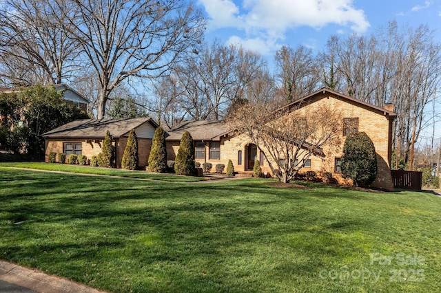 view of front of house featuring brick siding, a chimney, and a front lawn