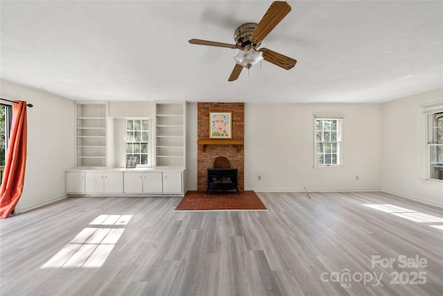 unfurnished living room featuring a wood stove, light wood-style flooring, and baseboards