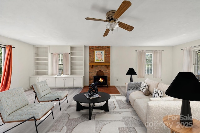 living area featuring ceiling fan, a fireplace, and wood finished floors