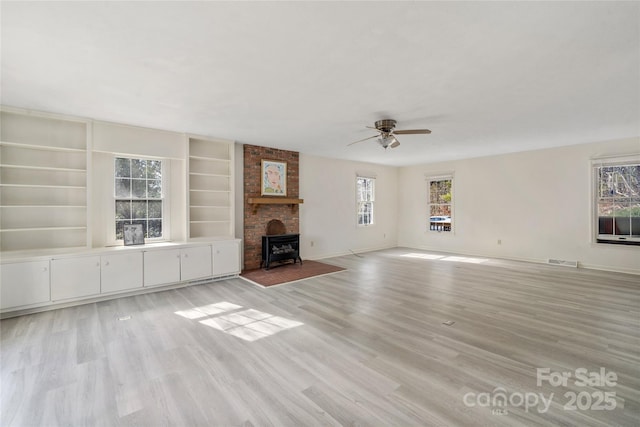 unfurnished living room featuring light wood-type flooring, visible vents, ceiling fan, and baseboards