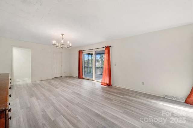 spare room with light wood-style floors, visible vents, a notable chandelier, and baseboards