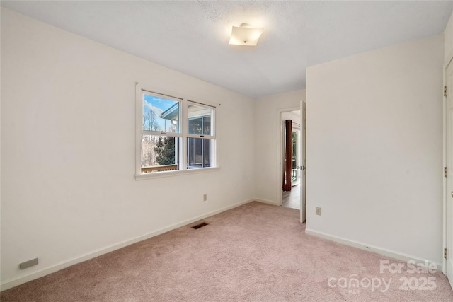 spare room featuring visible vents, light carpet, and baseboards